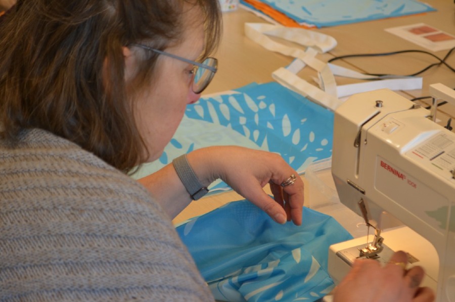 cursist naait met naaimachine aan een turnzakje van GO! vlag